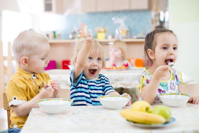 Kinder essen am Tisch in einer Kita