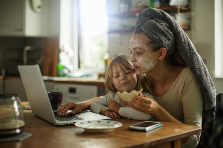 Eine Frau sitzt mit einem Kleinkind vor einem Laptop