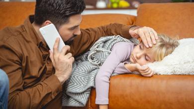 
		Vater sorgt sich um krankes Kind auf der Couch
	