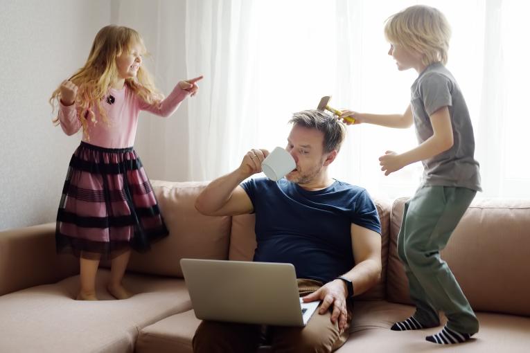 Vater sitz auf Couch mit zwei Kindern die hüpfen