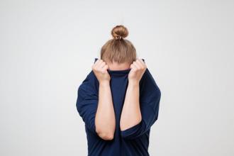 Frau versteckt ihren Kopf im Pullover
