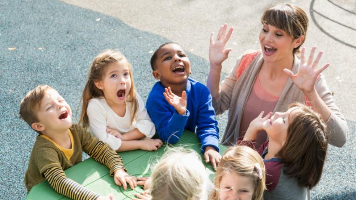 Erzieherin und Kinder spielen im Freien