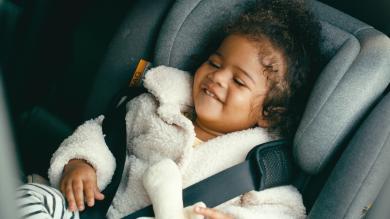 
		Kleines Baby sitzt im Auto im Kindersitz und lacht
	