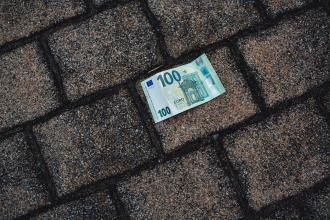 
		Ein 100-Euroschein liegt auf dem Asphaltboden
	