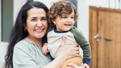 
		Eine weiblich gelesene Kindertagespflegeperson mit Kind auf dem Arm
	
