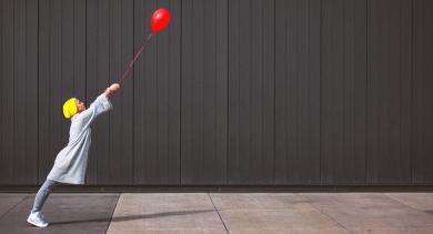 
		Eine Frau lässt sich von einem roten Luftballon ziehen
	