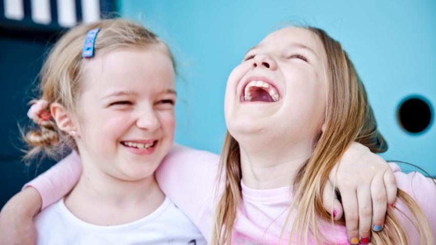 
		Zwei lachende kleine Mädchen umarmen sich
	