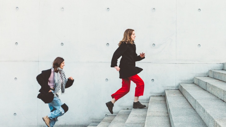 Zwei Frauen rennen die Treppe hintereinander hoch