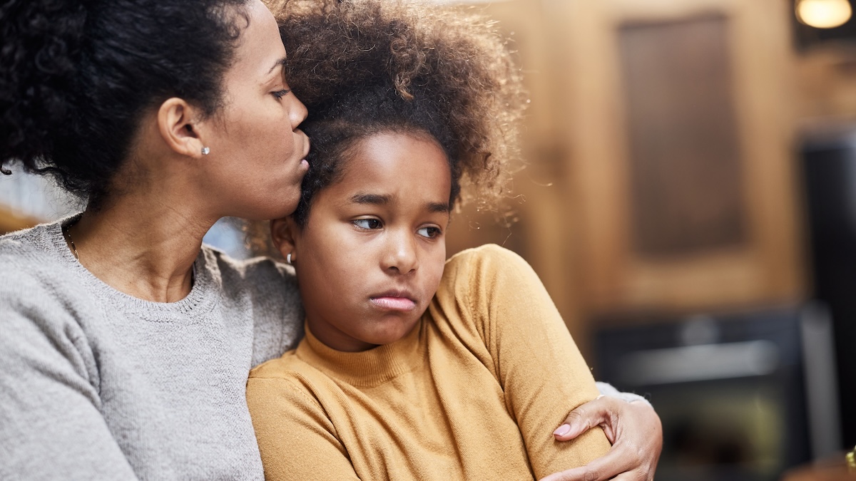 Mutter tröstet ihr traurige Tochter und gibt ihr Kuss auf die Strin