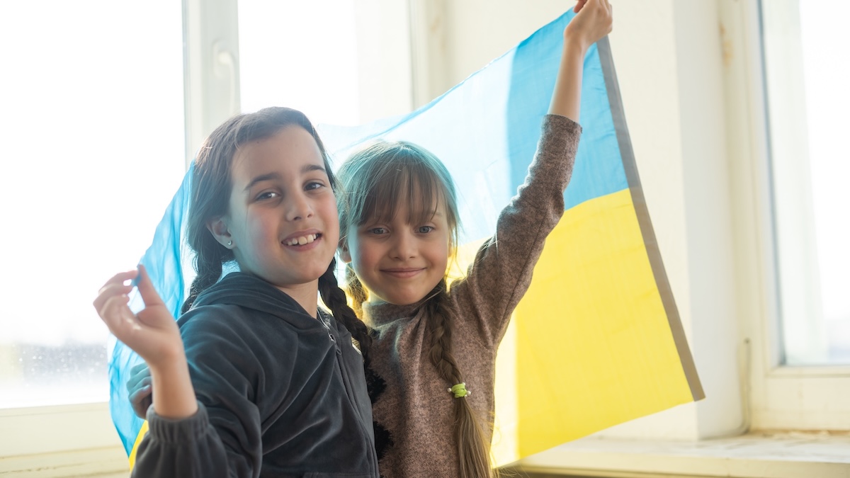 Zwei ukrainische Mädchen halten eine ukrainische Flagge hoch