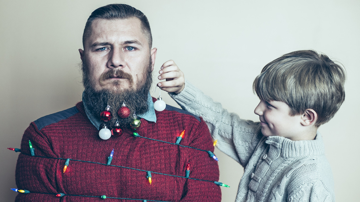 Junger Vater im Stress wird von Kind mit Weihnachtsdeko behängt