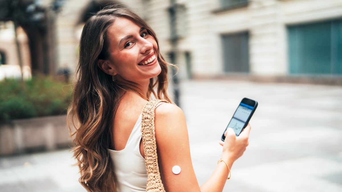 Junge Frau mit CGM Sensor und Handy