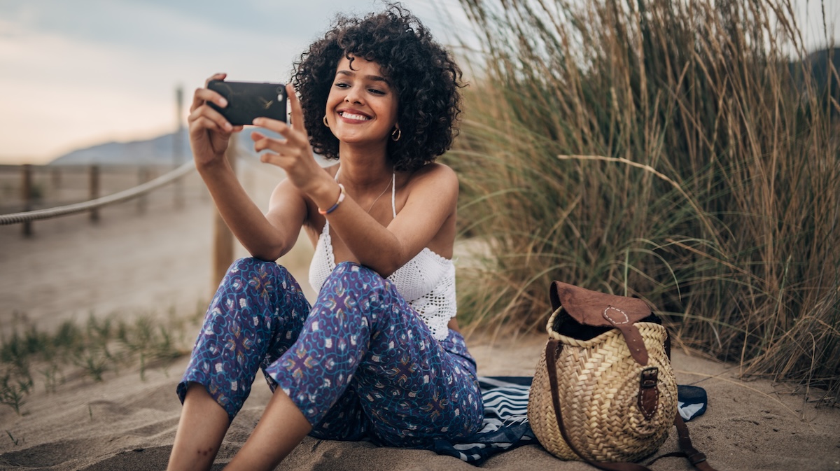 Lachende Frau fotografiert mit Handy im Urlaub